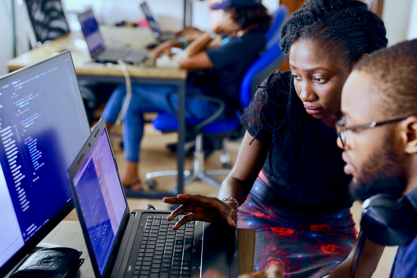 A researcher mentoring a fellow at a laptop, reviewing code together